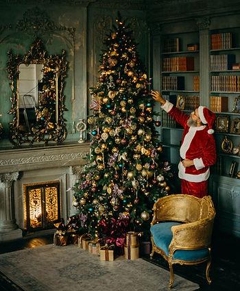 man in santa suit decorating christmas tree